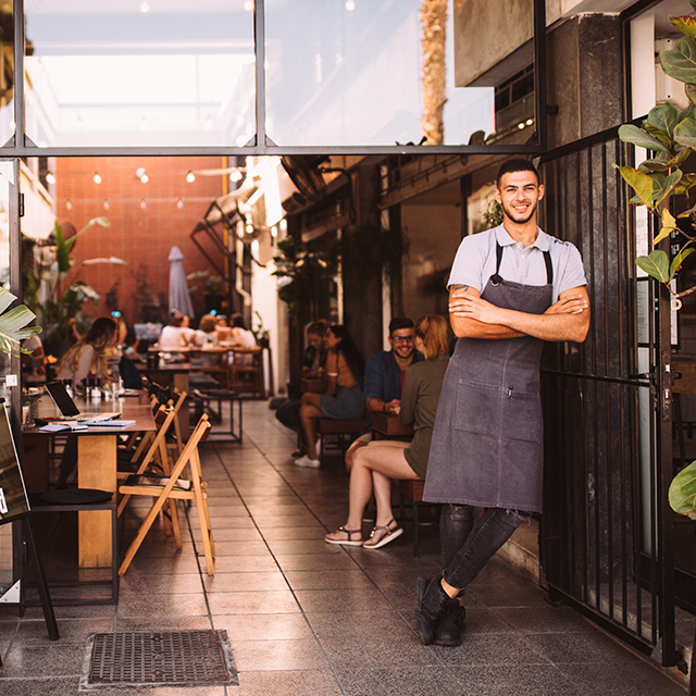 A young male business owner standing outside hipster urban café